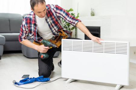 Technician fixing a home heater unit in a living room in El Paso