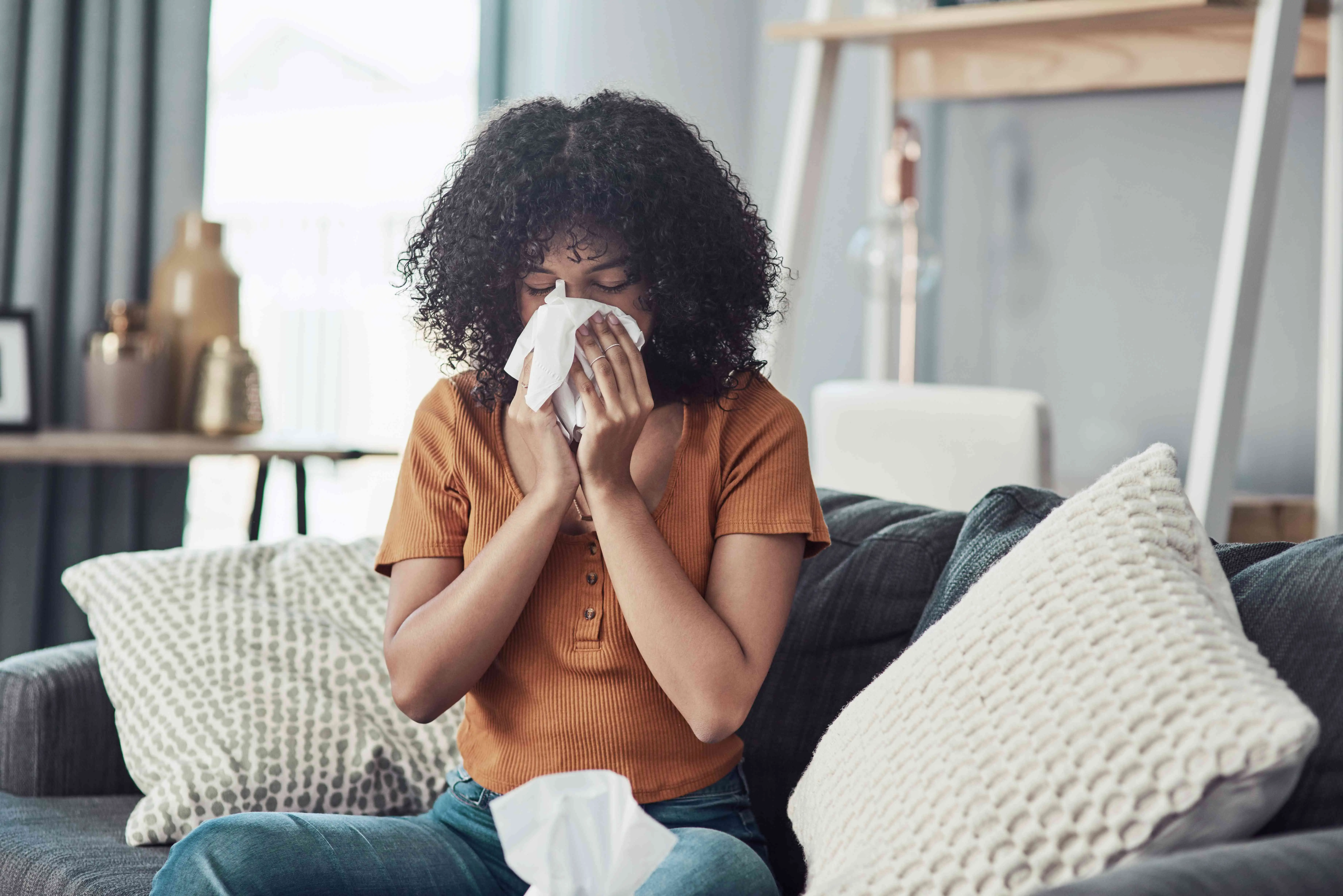 Person sneezing due to dust in their home