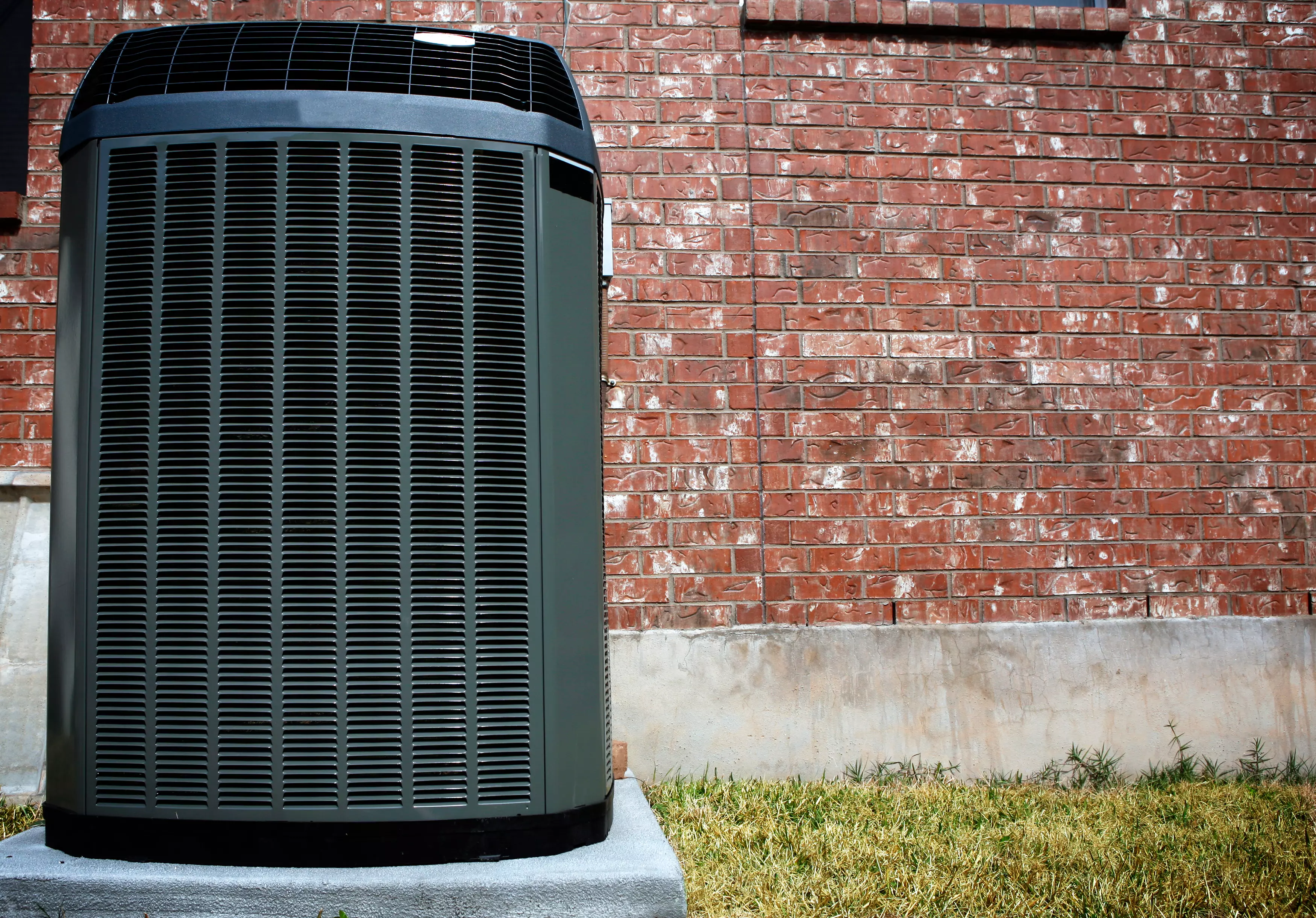 Outside air conditioning unit against brick home.