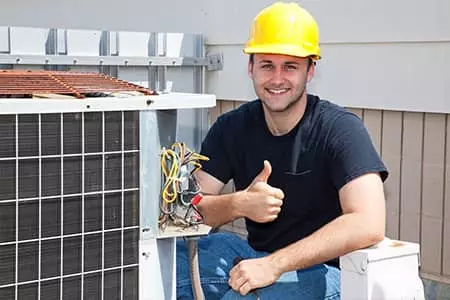 Guy giving thumbs up as he works on air conditioning system outside.