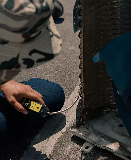 Using a tool to check the freon which is a common air conditioning issue.