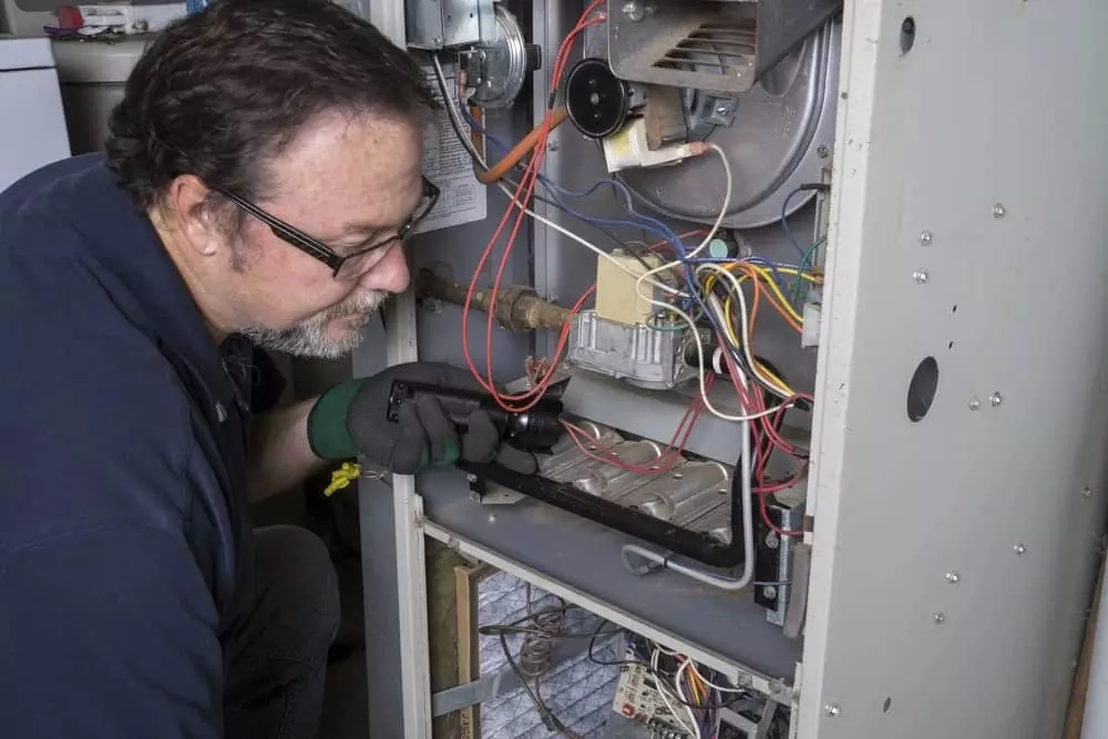 Guy performing maintenance on furnace. 